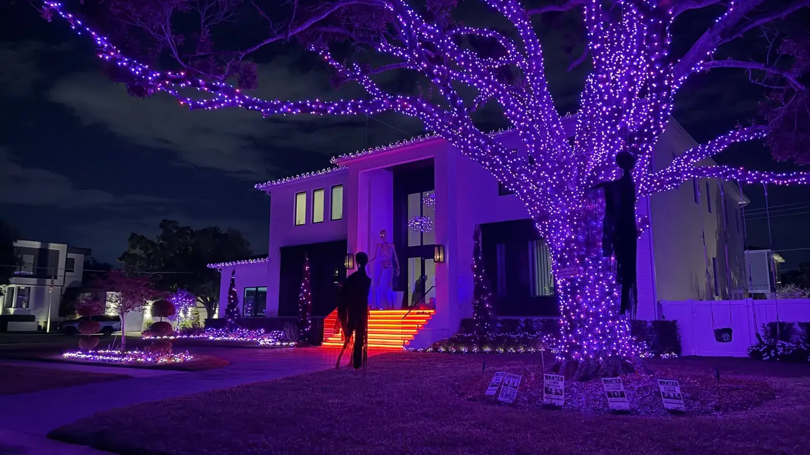 Real Tampa home with an oak wrapped in purple lights and orange uplighting for Halloween